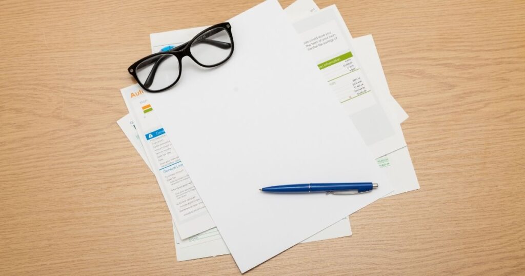 デスクに置かれた相続関連書類と眼鏡、ペン。相続放棄の必要書類を整理して準備している様子
