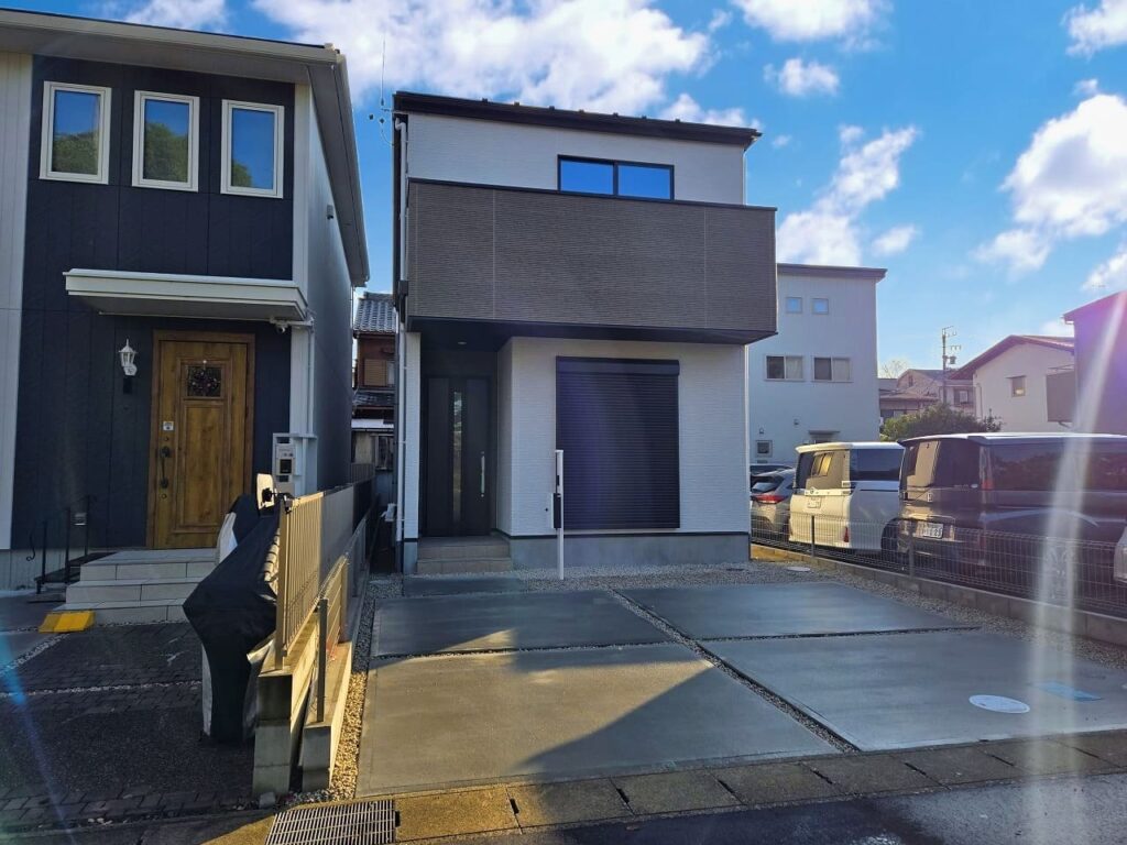 稲沢市小池一丁目の新築戸建て完成後外観。スタイリッシュな外観デザインとゆとりのある2台分の駐車スペース。朝日が差し込む明るい住宅街の一角。