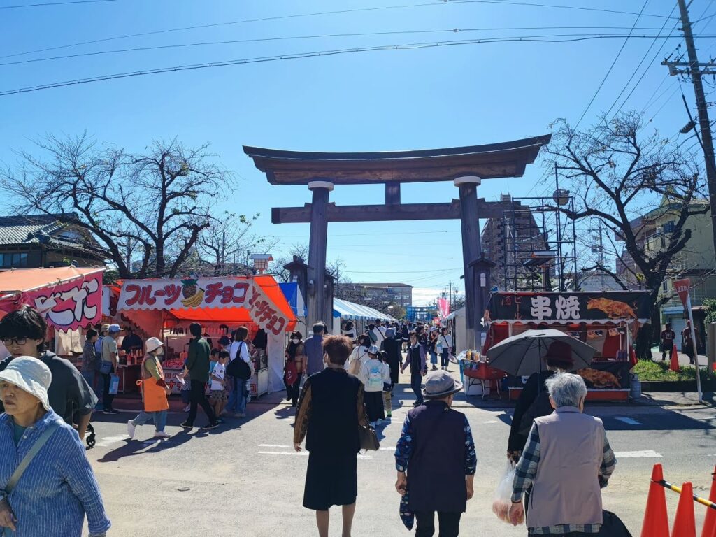 稲沢まつり2025 国府宮神社鳥居と参道 青空の下で賑わう来場者と屋台