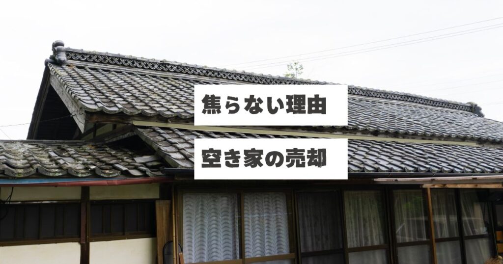 古い日本家屋の瓦屋根とレースカーテンがかかった窓が見える空き家の外観。画像には「焦らない理由 空き家の売却」というテキストが重ねられている。空き家の売却を焦らず、買手を募る前に建物解体と測量を先行して進める理由を説明する稲沢あんしん不動産の記事アイキャッチ画像。アスベスト、地中埋設物、面積不足など、進めていく中で出てくるかもしれない問題発生のリスクを事前に潰すことで売主を守る考え方を表現している。相続した実家や家じまいでの売却準備の重要性を伝える内容。