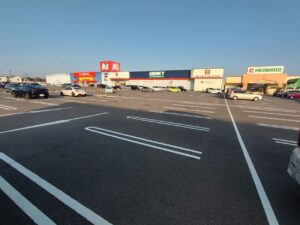 ニッケタウン稲沢の全景写真。左からケーズデンキ、ゲンキー(GENKY)、平和堂、平和堂フーズマーケットのテナントが並ぶ大型ショッピングセンター。広大な駐車場には白線が引かれ、多数の車両が停車している