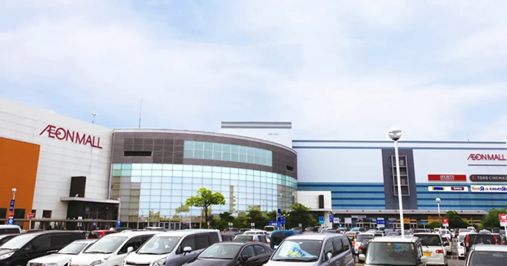 イオンモール木曽川の外観写真。AEON MALLのロゴが掲げられた建物と広い平面駐車場、青空を背景にした施設全景。買い物客の姿は写っていない。