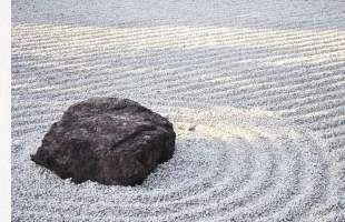 白砂に波紋状の砂紋を描いた枯山水の庭園。中央に黒い岩石が据えられ、周囲に同心円状の筋が丁寧に描かれている。天守前の広場で見られる、静かで落ち着いた和の景色。