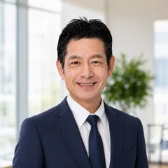 佐藤高樹の正面からの笑顔のバストアップ写真。オフィスの窓を背景に、穏やかで誠実な表情を伝えるプロフィール写真。