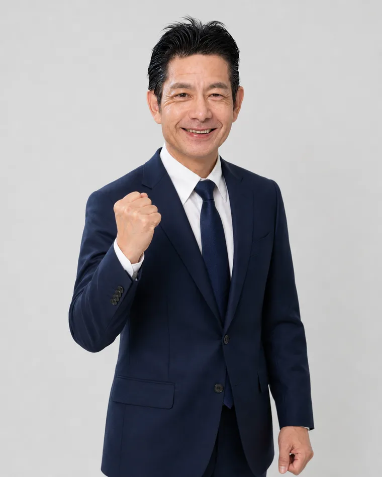 稲沢あんしん不動産 代表 佐藤高樹が、胸の前で拳を握り「よし、やるぞ」と気合いを込めた明るい笑顔で立っている写真。紺色のスーツ姿で、不動産売却の相談に全力で取り組む姿勢が伝わる。