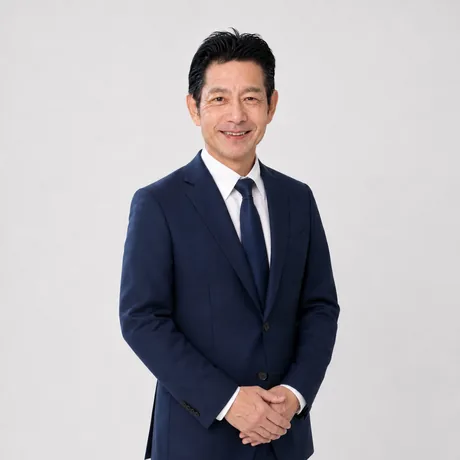 佐藤高樹が両手を体の前で軽く重ねて立ち、穏やかな笑顔を見せている写真。査定から引渡しまで担当者が変わらず対応することを表す立ち姿。