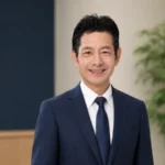 稲沢あんしん不動産 代表 佐藤高樹の上半身写真。紺スーツに白シャツ、自然な笑顔でこちらを見ている。