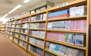 稲沢市立平和町図書館の館内、天井近くまで届く木製書棚にコミック(漫画)の背表紙がぎっしりと並ぶ書架の様子。蔵書量の多さが伝わる構図。