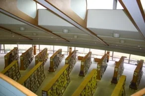 祖父江の森図書館の一般開架室を見下ろした館内写真。扇形（放射状）に配置された木製書棚が並び、吹き抜けの天井の高窓から自然光が差し込む開放的な空間。