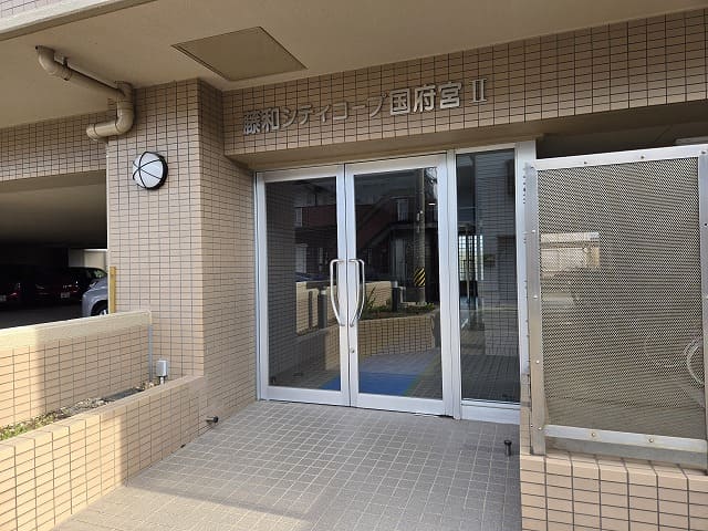 藤和シティコープ国府宮Ⅱのエントランス正面。建物名の銘板が掲げられたガラス扉の入り口が写っている。